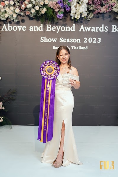 Award-winning Maine Coon breeder Anchalee Suwannthed holding FUR rosette and crystal trophy at Above and Beyond Awards 2023 in Thailand